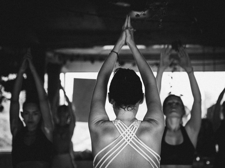 Gruppe beim Yoga – gemeinsame Haltung mit erhobenen Armen